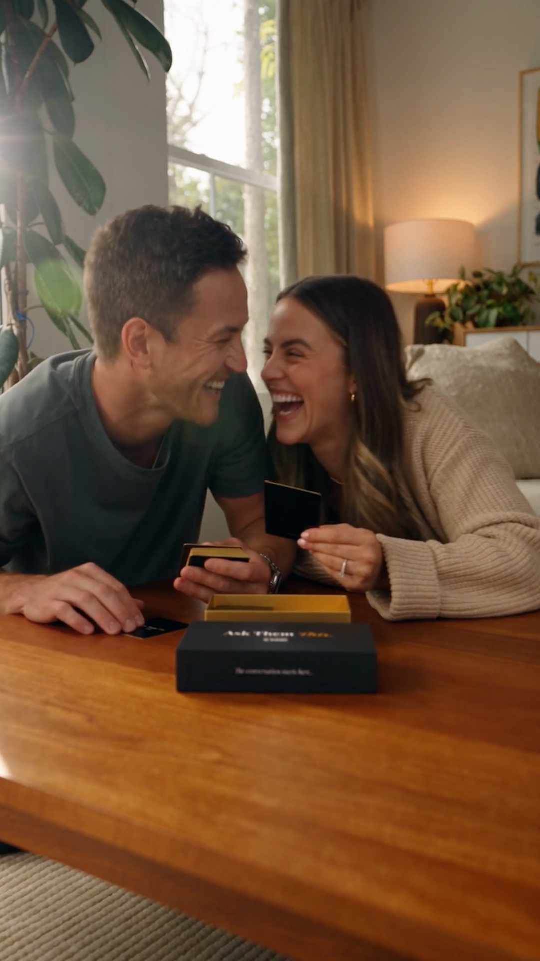 A couple laughing while playing the Ask Them This card game